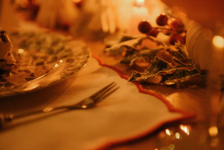 close up tablescape of placemat, decorated plate, fork and holly on a dining table